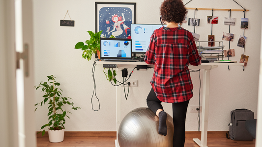 Person working at standing desk with foot on exercise ball in home office