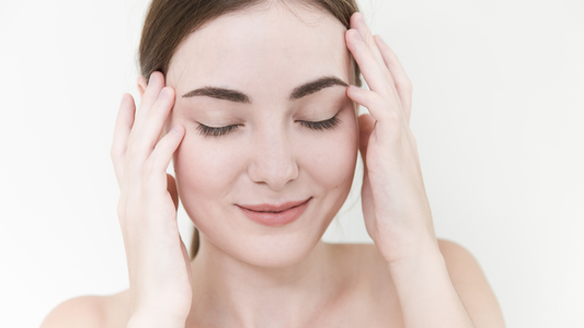 Woman gently massaging temples with eyes closed and slight smile