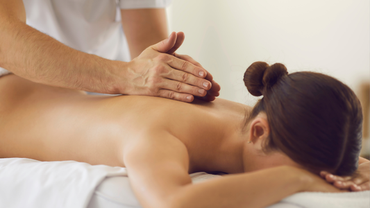 Massage therapist working on a woman's back in a spa setting