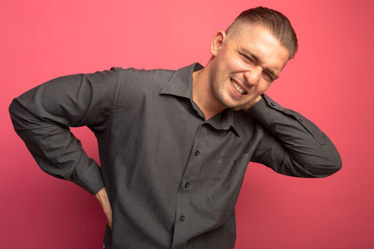 A man grimaces because of upper back pain.