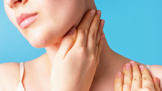 Close-up of woman massaging neck against a blue background
